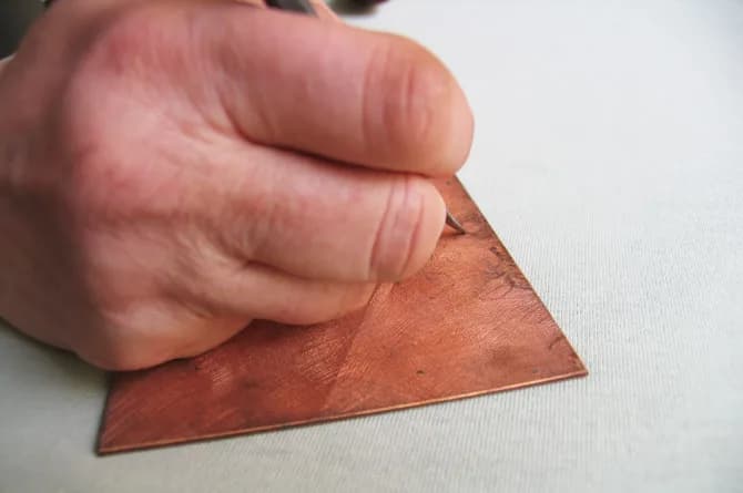 The plate further on and noticeably darker, a hand steadying it while the tool cuts into the ground.