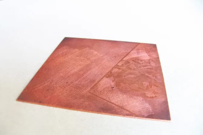 The plate rocked through and darkened, with the first light scraped back out along one side of a scored diagonal.