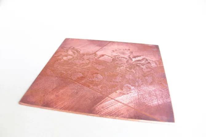 The image opening up across the plate — flower forms burnished out of the dark ground in the upper half.
