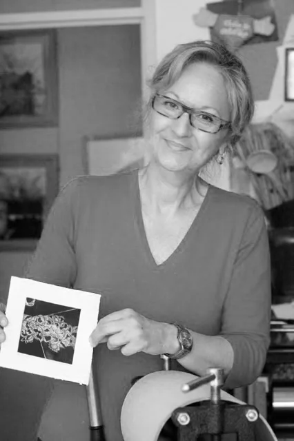 Maja Ilić in her studio, smiling, holding the finished print beside the roller of an etching press.